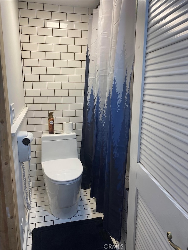 bathroom with tile walls, a shower with curtain, tile patterned floors, and toilet