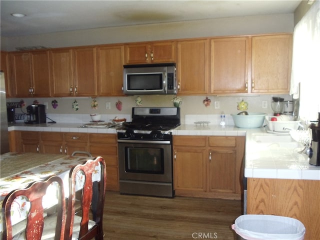 kitchen featuring tile countertops, stainless steel appliances, and dark hardwood / wood-style flooring