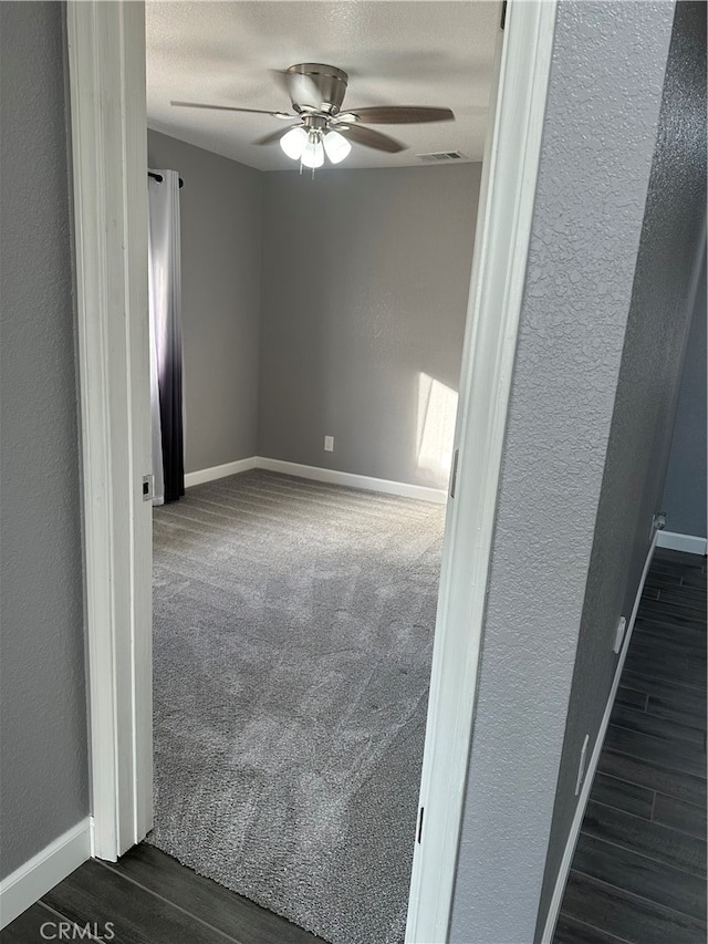 empty room with dark wood-type flooring and ceiling fan