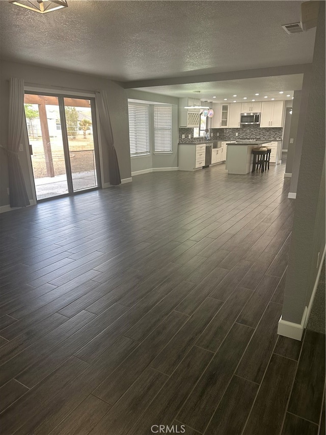 unfurnished living room with a textured ceiling and dark wood-type flooring