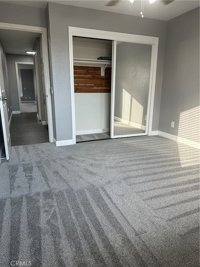 unfurnished bedroom with a closet, dark colored carpet, and ceiling fan