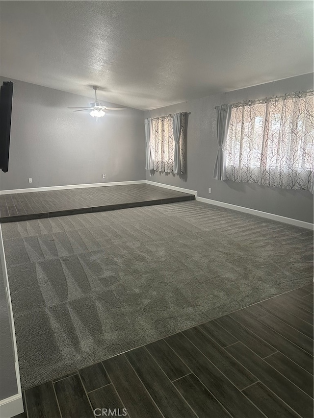 unfurnished room with ceiling fan, a textured ceiling, and dark carpet