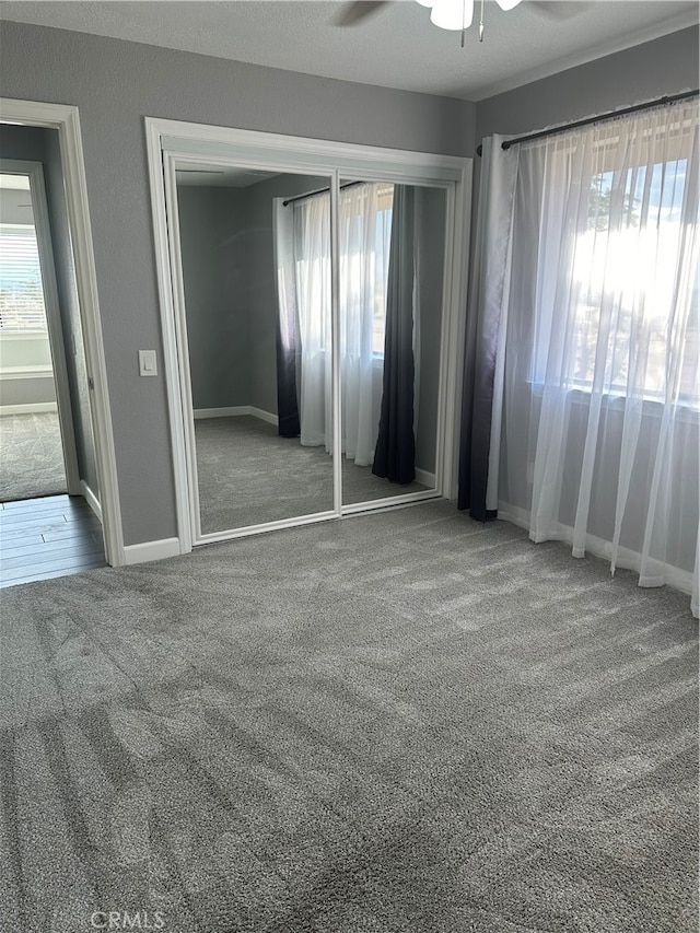 unfurnished bedroom with ceiling fan, a closet, carpet flooring, and multiple windows