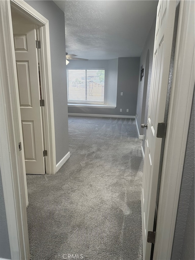 hall featuring carpet and a textured ceiling