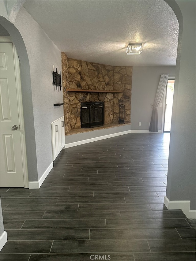 unfurnished living room with a textured ceiling, a fireplace, and dark hardwood / wood-style flooring