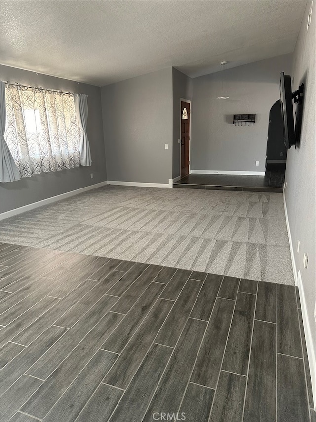 empty room with a textured ceiling and dark hardwood / wood-style floors