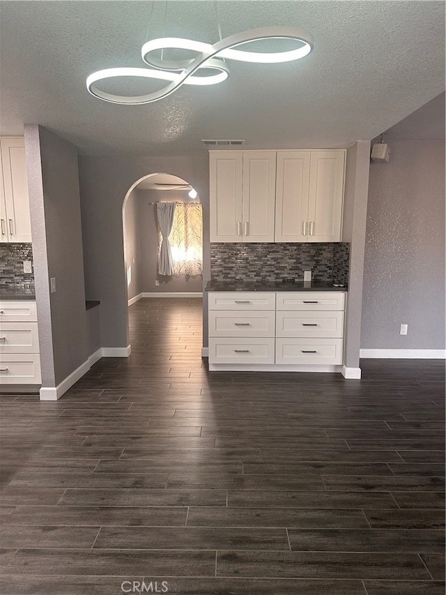 kitchen featuring a textured ceiling, dark wood-type flooring, tasteful backsplash, and white cabinetry