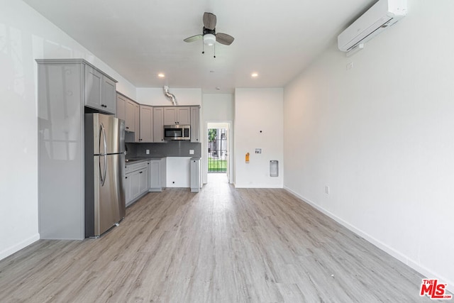 kitchen featuring gray cabinets, light wood-type flooring, ceiling fan, stainless steel appliances, and a wall mounted air conditioner