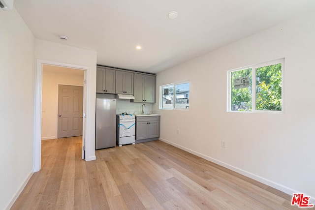 kitchen featuring light hardwood / wood-style floors, white range oven, stainless steel fridge, and gray cabinets