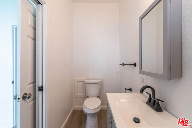 bathroom with hardwood / wood-style flooring, vanity, and toilet