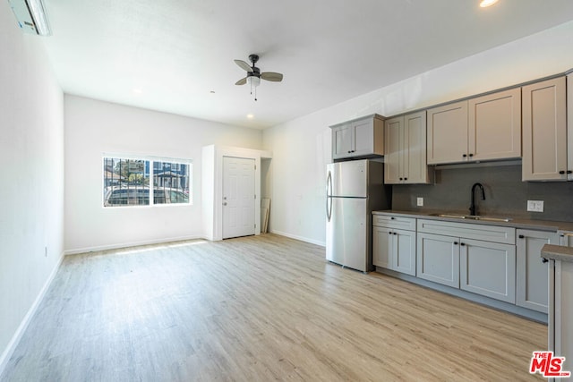 kitchen with ceiling fan, stainless steel fridge, sink, light hardwood / wood-style floors, and gray cabinets