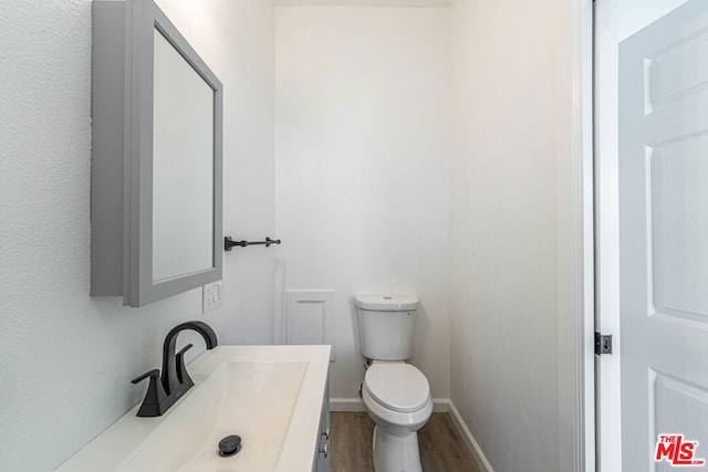 bathroom with wood-type flooring, vanity, and toilet