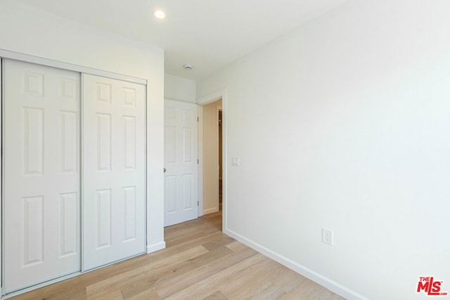 unfurnished bedroom featuring light wood-type flooring and a closet