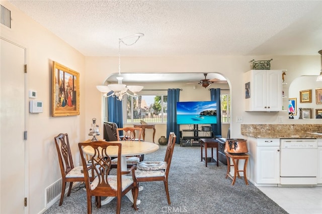 carpeted dining room featuring ceiling fan with notable chandelier and a textured ceiling