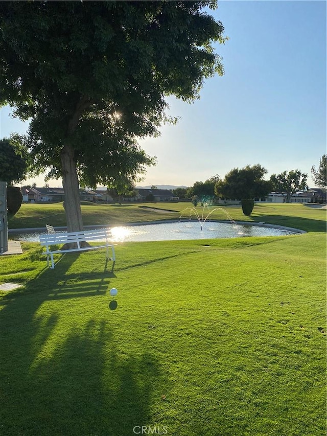 surrounding community with a water view and a lawn