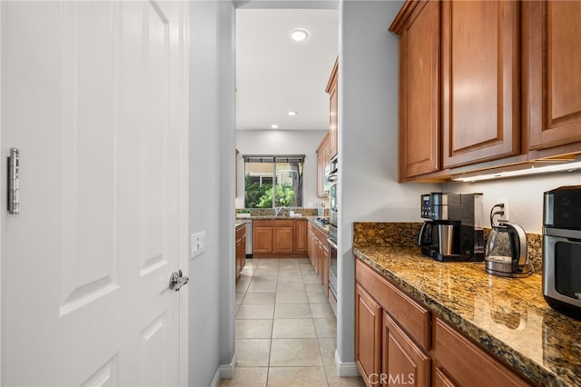 kitchen featuring sink, light tile patterned floors, and dark stone countertops