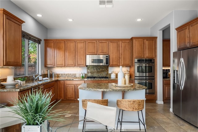 kitchen featuring light stone countertops, a kitchen breakfast bar, appliances with stainless steel finishes, and a center island