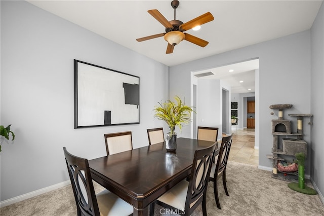 dining room with ceiling fan and light carpet