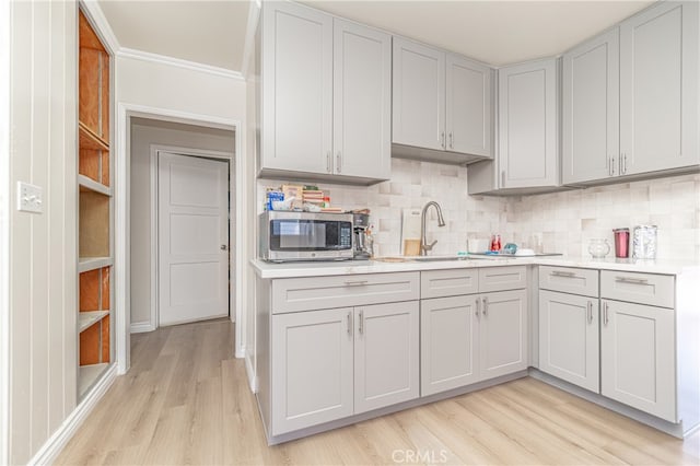 kitchen with ornamental molding, sink, light hardwood / wood-style floors, and decorative backsplash