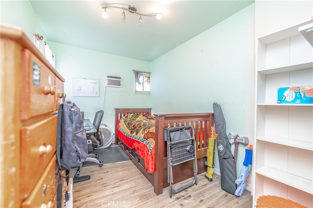 bedroom with a wall unit AC and light hardwood / wood-style floors