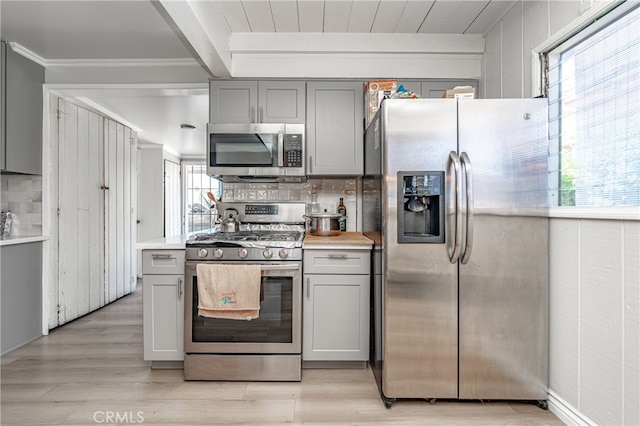 kitchen featuring tasteful backsplash, gray cabinetry, light hardwood / wood-style flooring, stainless steel appliances, and crown molding