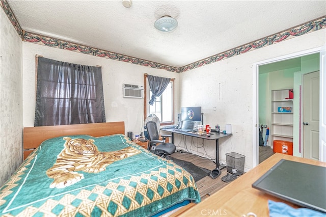 bedroom featuring a textured ceiling, a wall mounted AC, and hardwood / wood-style flooring