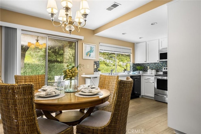 dining space with light wood-type flooring, visible vents, and a notable chandelier