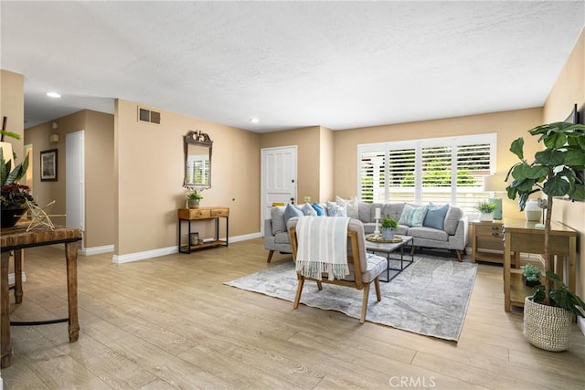 living area featuring recessed lighting, visible vents, a textured ceiling, light wood-type flooring, and baseboards