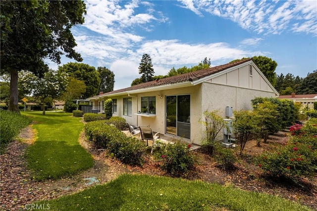 rear view of property featuring stucco siding, board and batten siding, and a yard