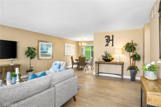 living room with light wood-type flooring, baseboards, and a notable chandelier