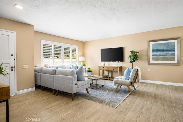 living area with a textured ceiling, light wood finished floors, and baseboards