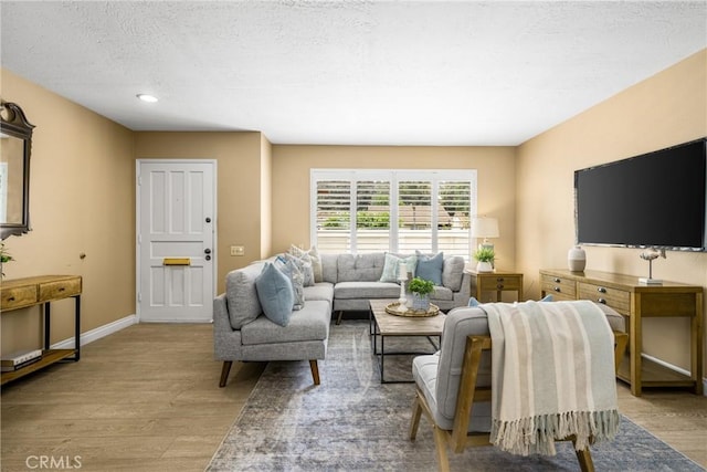 living area featuring recessed lighting, a textured ceiling, baseboards, and wood finished floors