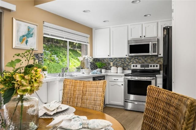 kitchen with light countertops, decorative backsplash, appliances with stainless steel finishes, white cabinets, and a sink