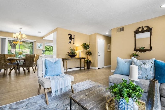 living area with a notable chandelier, recessed lighting, visible vents, light wood-style floors, and baseboards