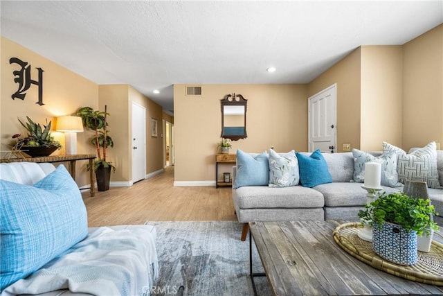 living room with light wood finished floors, baseboards, visible vents, and recessed lighting