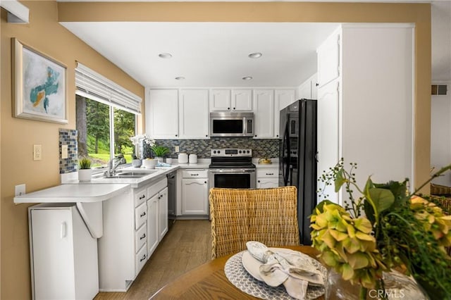 kitchen with light countertops, decorative backsplash, appliances with stainless steel finishes, white cabinets, and a sink