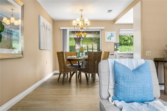 dining room with a chandelier, visible vents, baseboards, and wood finished floors