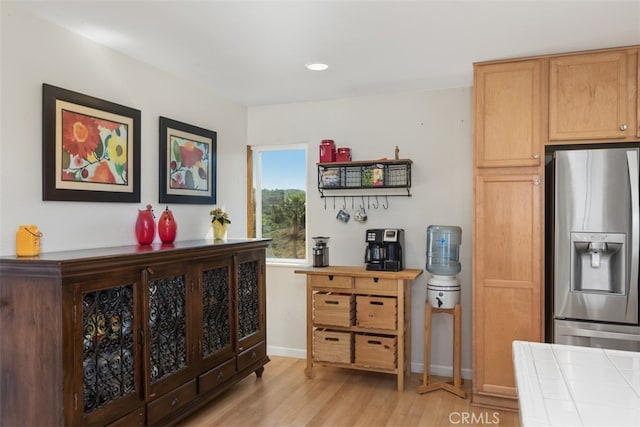 kitchen with light hardwood / wood-style flooring, tile countertops, and stainless steel fridge with ice dispenser