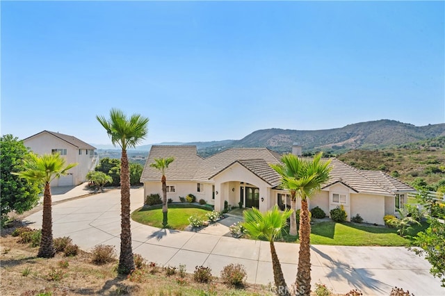 view of front facade with a front yard, a garage, and a mountain view