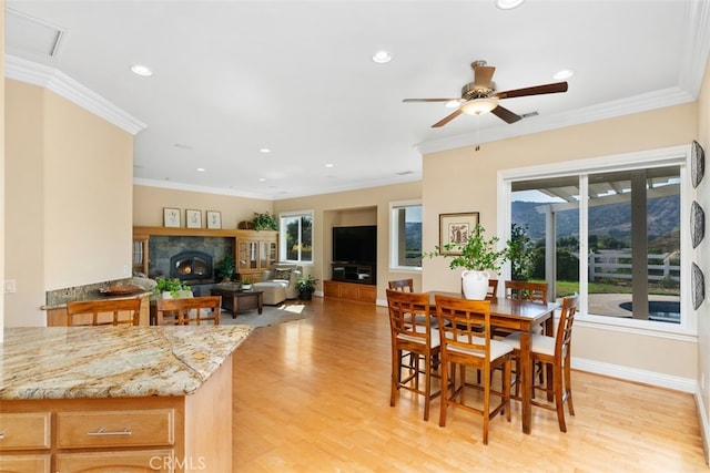 dining space with light hardwood / wood-style floors, ornamental molding, and ceiling fan