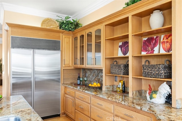 kitchen with stainless steel built in fridge, ornamental molding, and light stone countertops