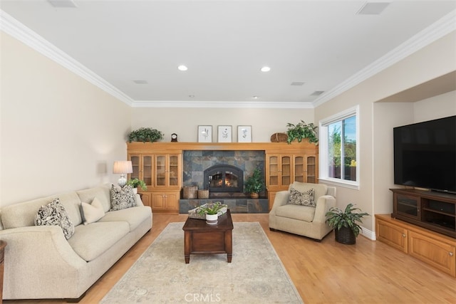 living room featuring light hardwood / wood-style floors, ornamental molding, and a tile fireplace