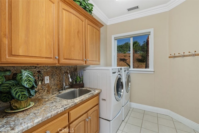 laundry room with washer and clothes dryer, light tile patterned floors, ornamental molding, sink, and cabinets