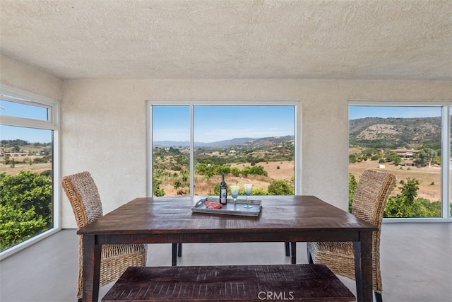 dining space featuring a mountain view, a textured ceiling, and concrete floors