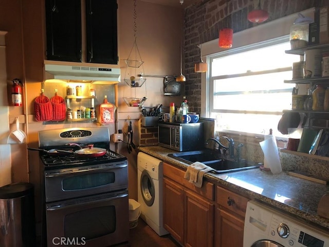 kitchen with washer / dryer, sink, stainless steel appliances, and dark stone counters