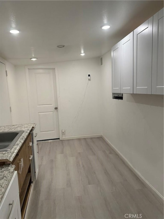 interior space with visible vents, baseboards, a sink, recessed lighting, and light wood finished floors