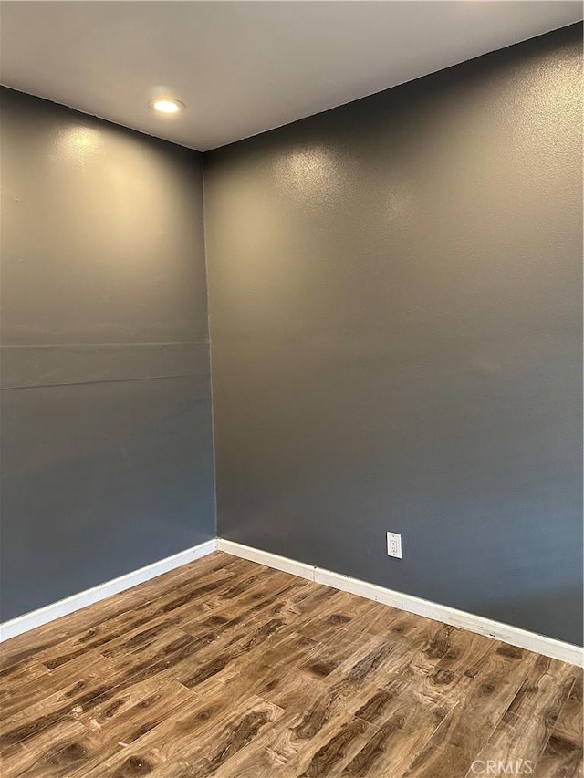 spare room with dark wood-type flooring, baseboards, and recessed lighting