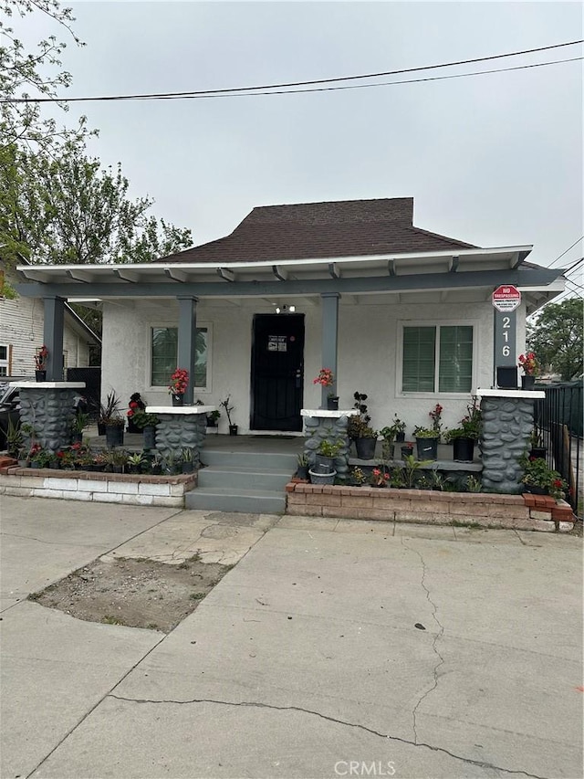 bungalow-style house with covered porch and stucco siding