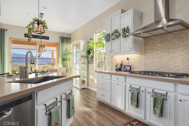 kitchen featuring stainless steel appliances, sink, wall chimney range hood, pendant lighting, and white cabinets