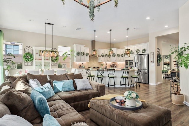 living room with a notable chandelier, dark hardwood / wood-style flooring, and sink